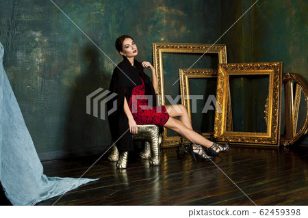beauty rich brunette woman in luxury interior near empty golden frames, lifestyle people concept 62459398