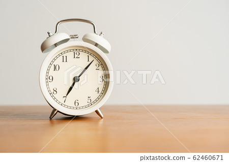 White alarm clock on brown wood desk and cream 62460671