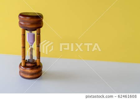 Selective focus of wooden hourglass on yellow Selective focus of wooden hourglass on yellow 62461608