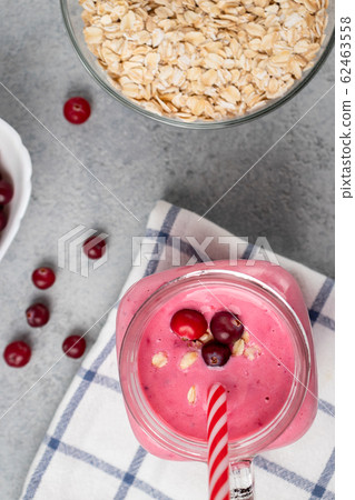 Freshly homemade smoothie with cranberries, oatmeal and yogurt in a mug jar on a gray table. Healthy eating concept. Vertical image, top view, flatlay 62463558
