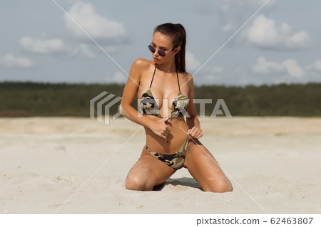 Sensual woman kneeling on beach 62463807