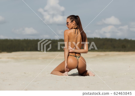 Seductive lady doing hair on beach 62463845