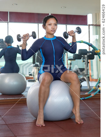 Woman exercises with dumbbells in the gym 62466419