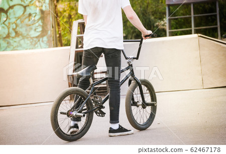 Teenage boy standing by bmx bike at skatepark 62467178