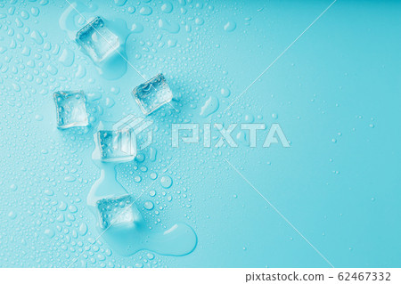Ice cubes with water drops scattered on a blue Ice cubes with water drops scattered on a blue 62467332