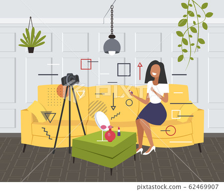 beauty blogger applying lipstick woman showing trend makeup tutorial recording online video with camera on tripod blogging concept living room interior horizontal full length beauty blogger applying lipstick woman showing trend makeup tutorial recording online video with camera on tripod blogging concept living room interior horizontal full length 62469907