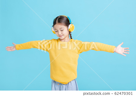 Happy little girl   listens to music in headphones 62470301