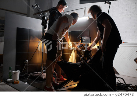 Video production backstage. Behind the scenes of creating video content, a professional team of cameramen with a director filming commercial ads. Video content creation, video creation industry. Low 62470478