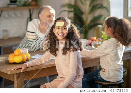 Two dark-skinned girls playing guess game with their granddad Two dark-skinned girls playing guess game with their granddad 62473333
