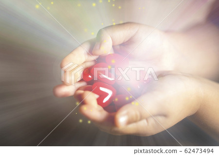 Child's hand with lots of red heart motifs shining Child's hand with lots of red heart motifs shining 62473494