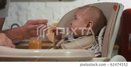 Mother feeding her baby in kitchen 62474552