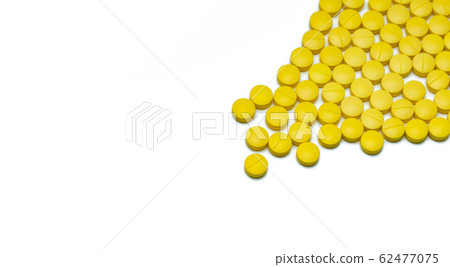 Yellow small round tablets pills on white 62477075