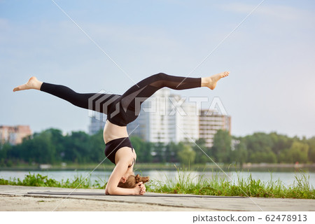 Young woman practicing yoga at city lake Young woman practicing yoga at city lake 62478913