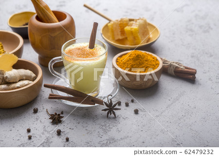 Turmeric powder, curcuma root, cinnamon, ginger over grey 62479232