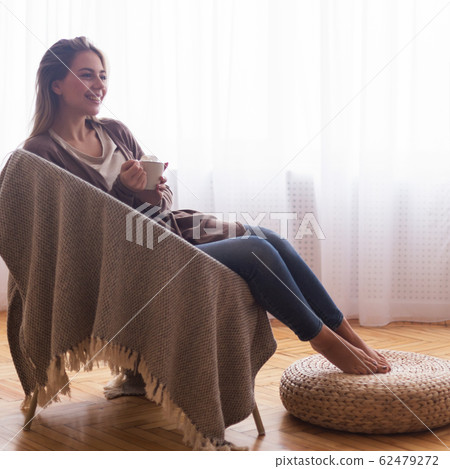 Cheerful woman resting with coffee at home 62479272