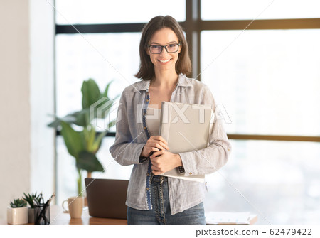 Happy manager smiling at camera in modern office Happy manager smiling at camera in modern office 62479422