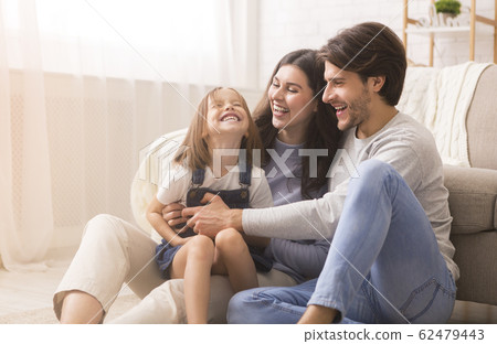 Playful Parents Tickling Their Little Daughter, Having Fun Together At Home Playful Parents Tickling Their Little Daughter, Having Fun Together At Home 62479443