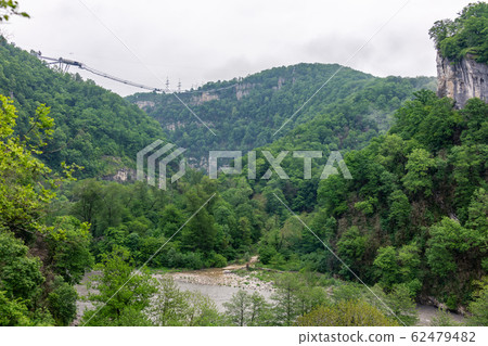 A gorge in the mountains with a suspension bridge A gorge in the mountains with a suspension bridge 62479482