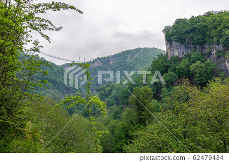 A gorge in the mountains with a suspension bridge A gorge in the mountains with a suspension bridge 62479484