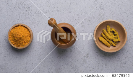 Curcuma in different shapes turmeric powder, root on concrete 62479545