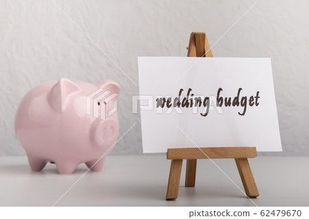 Pink piggy bank with note on easel and wedding word Pink piggy bank with note on easel and wedding word 62479670