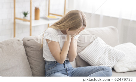 Desperate young woman crying on couch at home 62479753