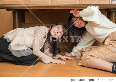 Parent and child hiding under the table due to earthquake 62480852