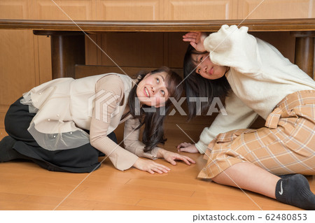 Parent and child hiding under the table due to earthquake 62480853