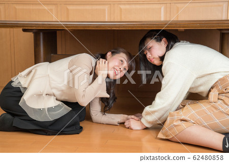 Parent and child hiding under the table due to earthquake 62480858