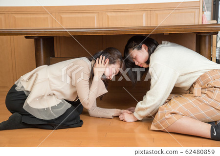 Parent and child hiding under the table due to earthquake 62480859
