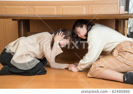 Parent and child hiding under the table due to earthquake 62480860