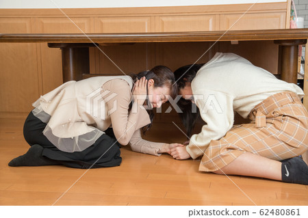 Parent and child hiding under the table due to earthquake 62480861