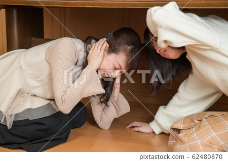 Parent and child hiding under the table due to earthquake 62480870