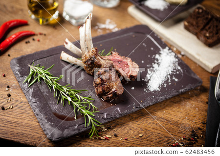 Grilled lamb chops served with a branch of rosemary Grilled lamb chops served with a branch of rosemary 62483456