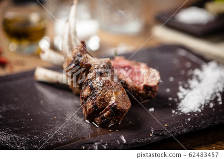 Grilled lamb chops served with a branch of rosemary Grilled lamb chops served with a branch of rosemary 62483457