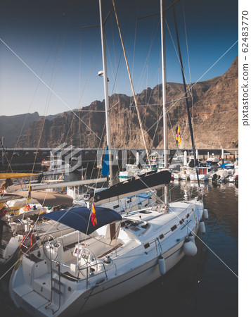 Toned image of expensive yachts moored in port against high cliffs and mountains 62483770