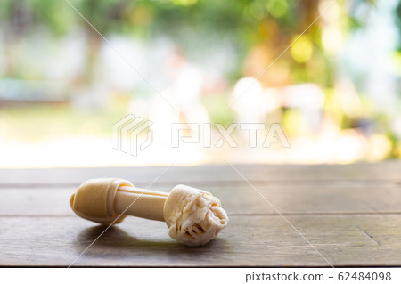 Dog bone, Ate Dog treats, Rawhide dog chews bitten on wooden table texture in bokeh green garden, Close up and Macro shot, Selective focus, Snack food dog concept 62484098