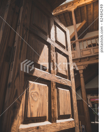 Closeup toned image of open wooden door leading to beautiful inner court of old house 62484249