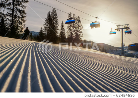 Fresh groomed snow with skier and ski lift chair  at background in resort Jasna at Low Tatras mountains , Slovakia 62484656