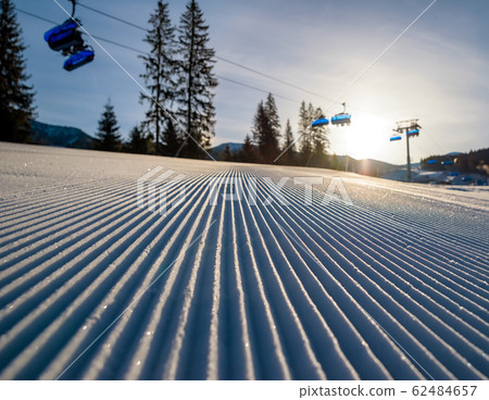 Fresh groomed snow and ski lift chair at background in resort Jasna at Low Tatras mountains , Slovakia Fresh groomed snow and ski lift chair at background in resort Jasna at Low Tatras mountains , Slovakia 62484657