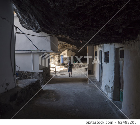 Tourist man at Cueva de Candelaria, Pirate cave Poris de Candelaria, small fisherman village hidden under rock cornice with white blue houses, attraction near Tijarafe, La Palma, Canary islands, Spain Tourist man at Cueva de Candelaria, Pirate cave Poris de Candelaria, small fisherman village hidden under rock cornice with white blue houses, attraction near Tijarafe, La Palma, Canary islands, Spain 62485203