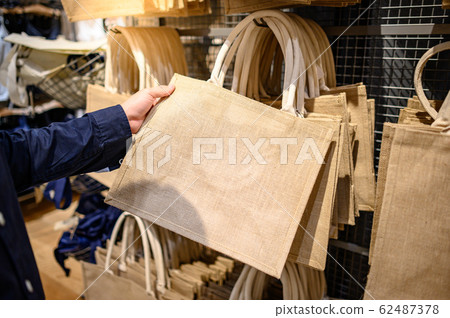 Male hand choosing Jute handbag in store 62487378