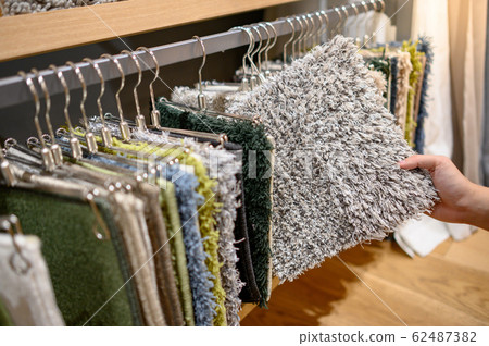 Male hand choosing fur carpet in furniture store 62487382