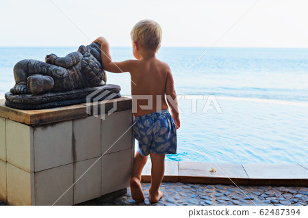 Young child at infinity swimming pool with sea Young child at infinity swimming pool with sea 62487394