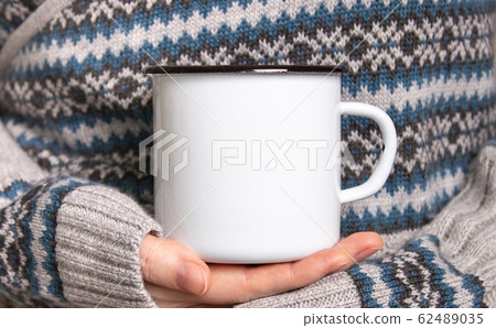 Enamel Mug with black edge line Mock-up. Girl holds white old-tin campfire cup in her hands 62489035
