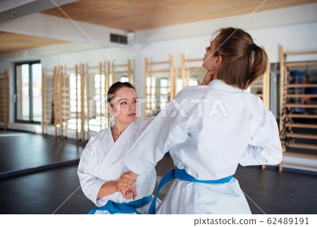 Young women practising karate indoors in gym. 62489191