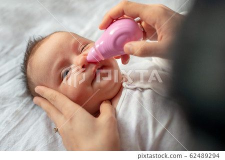 mother using baby nasal aspirator mucus nose suction 62489294