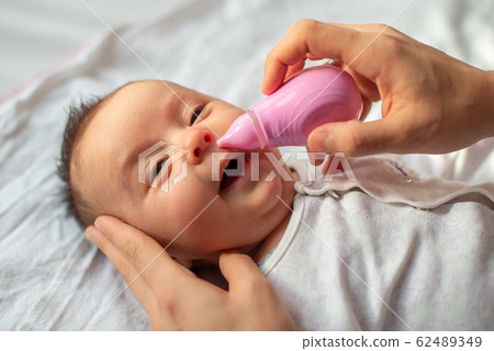mother using baby nasal aspirator mucus nose suction 62489349