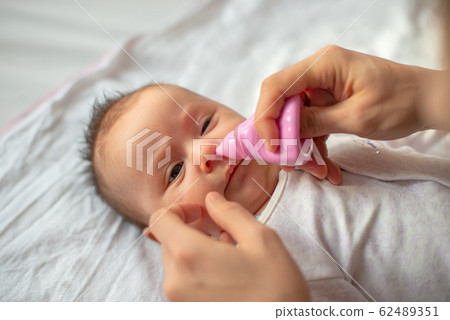 mother using baby nasal aspirator mucus nose suction 62489351