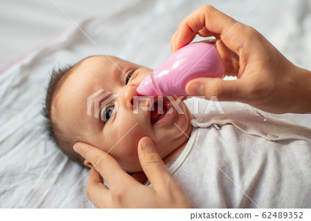 mother using baby nasal aspirator mucus nose suction 62489352